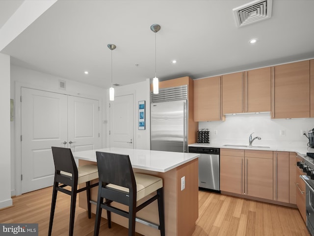 kitchen with light wood finished floors, appliances with stainless steel finishes, a sink, and visible vents