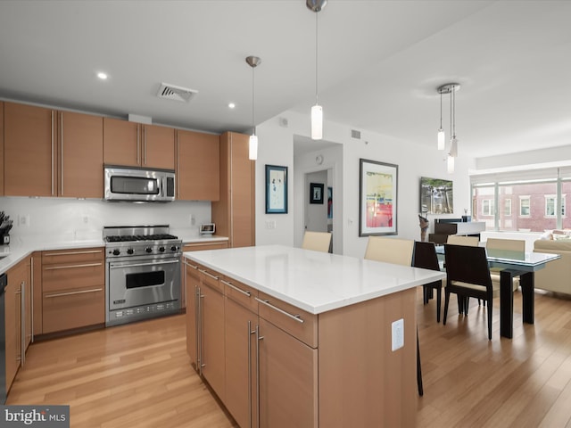 kitchen featuring light wood finished floors, visible vents, stainless steel appliances, light countertops, and pendant lighting