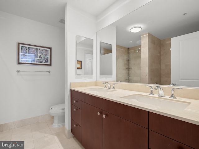 full bathroom featuring toilet, double vanity, a sink, and tiled shower