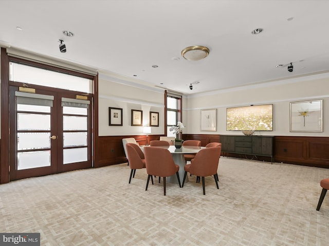 dining space with a wainscoted wall, light colored carpet, and french doors