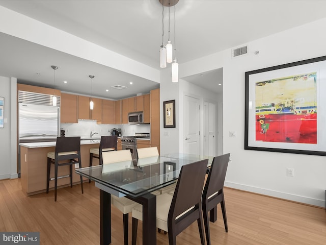 dining room with light wood finished floors, visible vents, baseboards, and recessed lighting