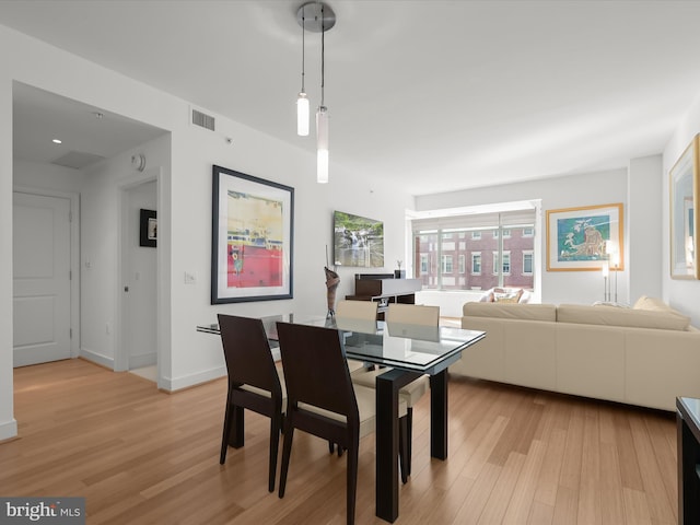 dining area featuring visible vents, light wood-style flooring, and baseboards