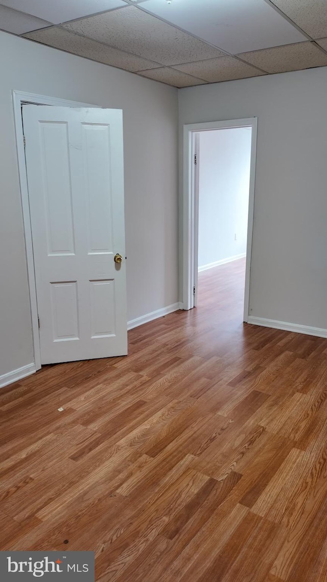 spare room with a drop ceiling and light hardwood / wood-style floors