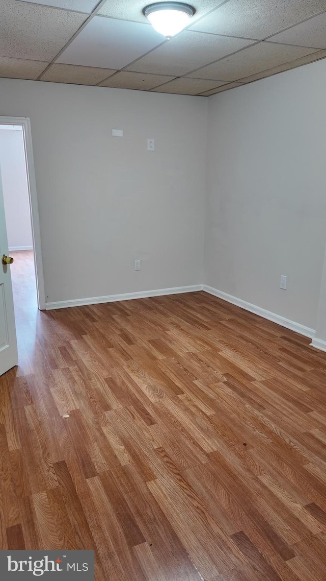 empty room with a drop ceiling and light hardwood / wood-style flooring