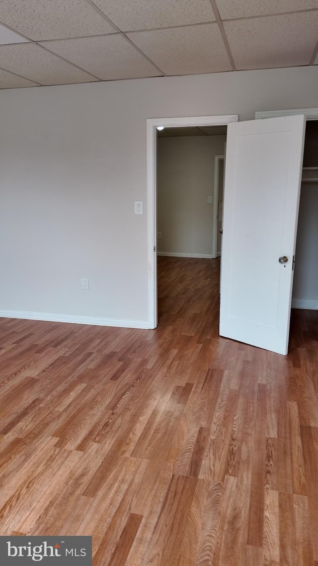 spare room featuring a paneled ceiling and hardwood / wood-style flooring