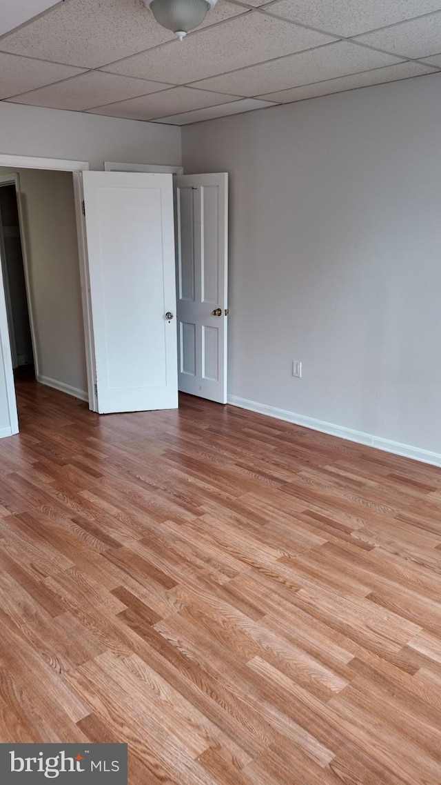 unfurnished room with light wood-type flooring and a paneled ceiling