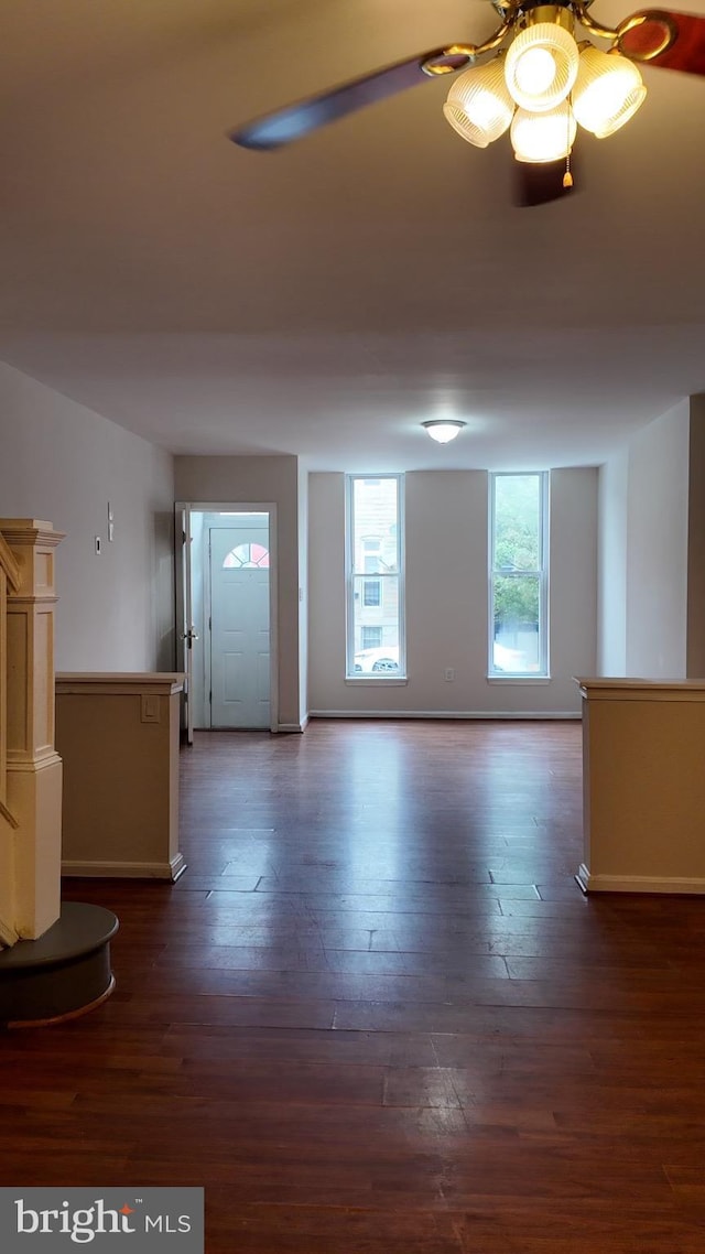 unfurnished living room with dark hardwood / wood-style flooring and ceiling fan