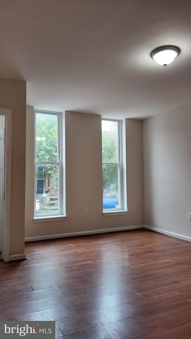 empty room featuring a healthy amount of sunlight and dark wood-type flooring