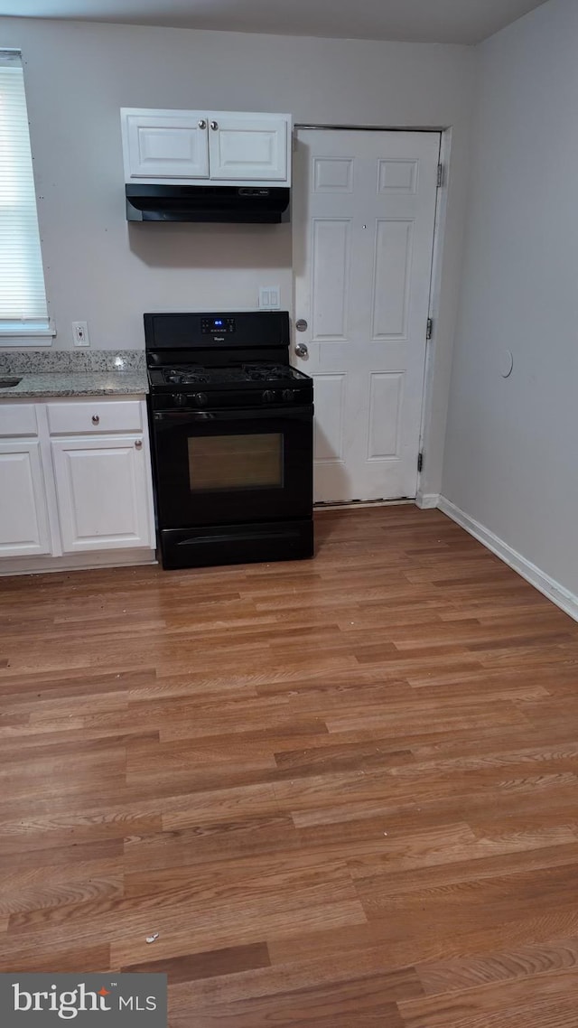 kitchen featuring black gas range, light wood-type flooring, and white cabinetry