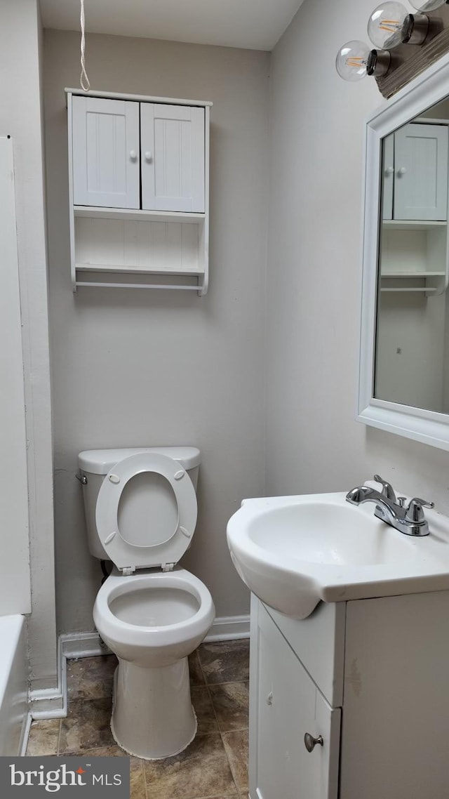 bathroom with a washtub, vanity, and toilet