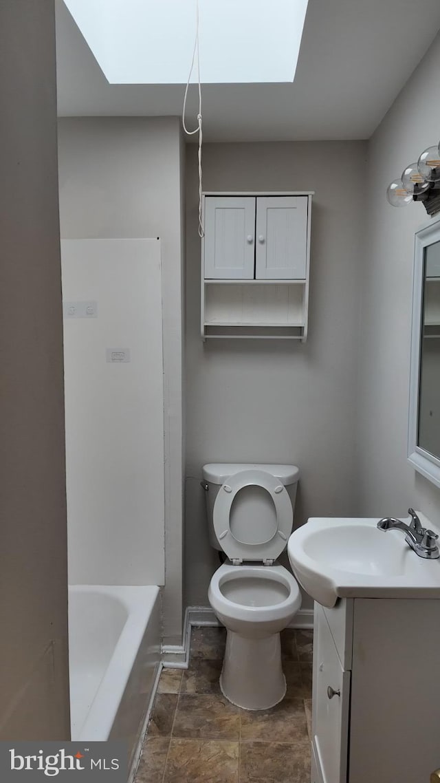 bathroom featuring vanity, toilet, and a skylight