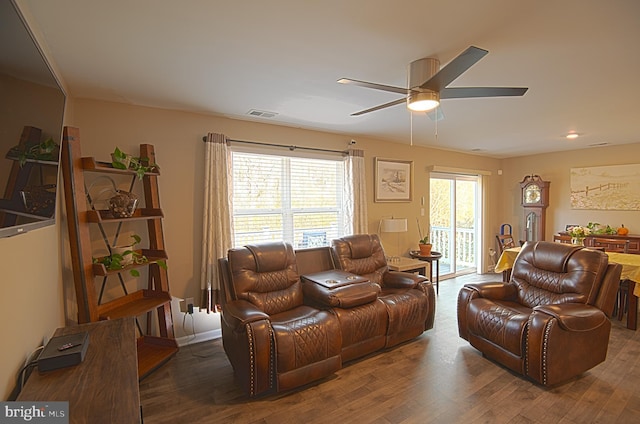 living room featuring dark hardwood / wood-style flooring, ceiling fan, and a healthy amount of sunlight