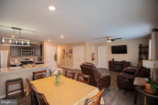 dining space with ceiling fan, sink, and dark wood-type flooring