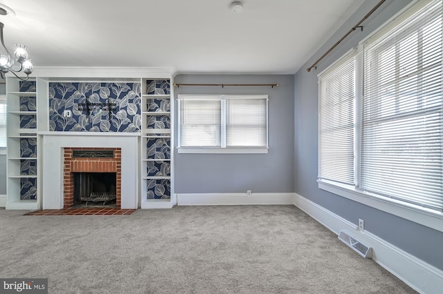 unfurnished living room with carpet flooring, an inviting chandelier, and a brick fireplace