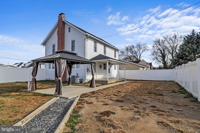 rear view of property featuring a gazebo and cooling unit