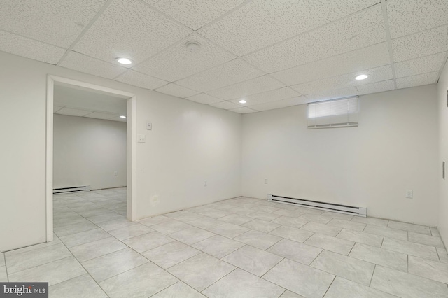 tiled spare room featuring a drop ceiling and baseboard heating