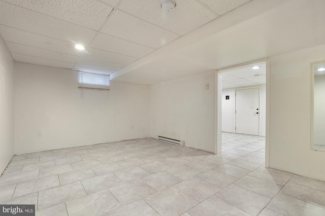 spare room with a paneled ceiling, light tile patterned floors, and baseboard heating