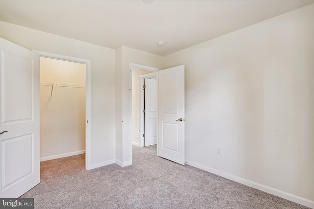 unfurnished bedroom with light colored carpet, a spacious closet, and a closet