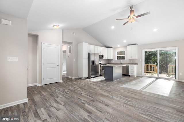 kitchen with white cabinetry, a center island, stainless steel appliances, lofted ceiling, and hardwood / wood-style flooring