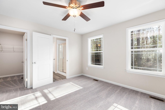 unfurnished bedroom with ceiling fan, a closet, carpet, and a spacious closet