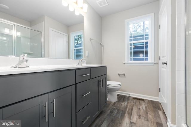 bathroom featuring hardwood / wood-style floors, vanity, toilet, and a shower with door