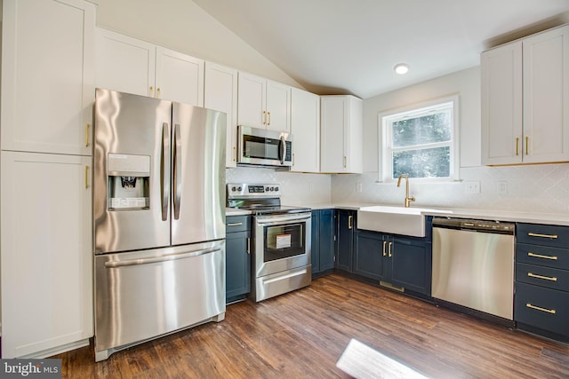 kitchen featuring dark wood-type flooring, sink, vaulted ceiling, appliances with stainless steel finishes, and white cabinetry