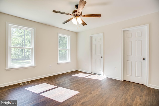 unfurnished bedroom featuring ceiling fan, dark wood-type flooring, and multiple windows