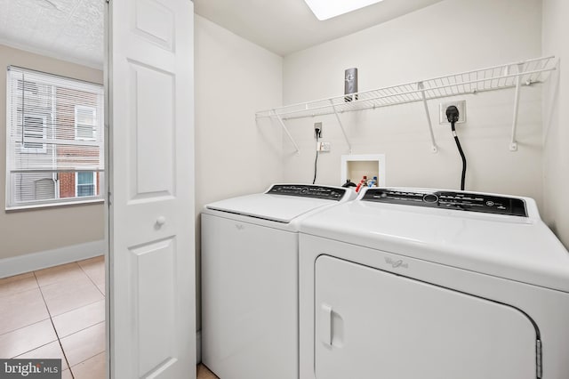 clothes washing area with light tile patterned flooring and washer and dryer