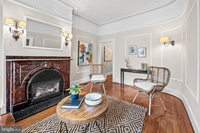 living area featuring a fireplace, hardwood / wood-style flooring, and crown molding