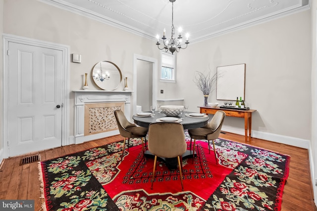 dining space with hardwood / wood-style flooring, ornamental molding, a high end fireplace, and an inviting chandelier