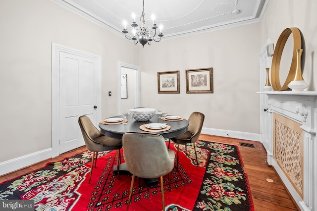 dining room featuring hardwood / wood-style floors, crown molding, and a notable chandelier