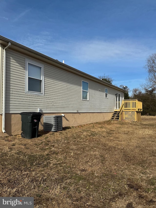 view of home's exterior featuring a deck, cooling unit, and a yard