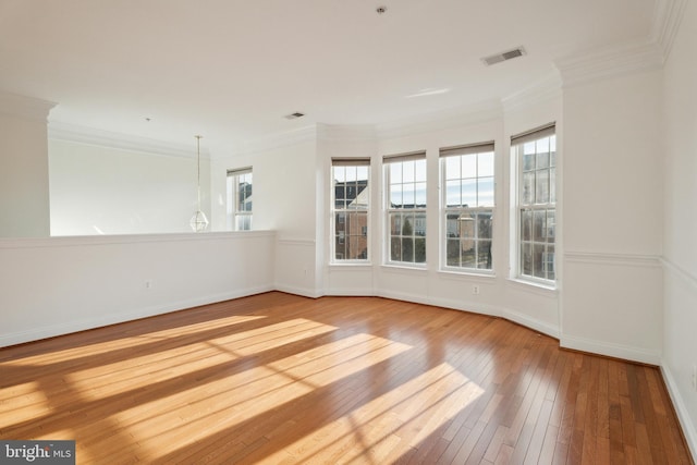 spare room featuring hardwood / wood-style flooring, crown molding, and a healthy amount of sunlight