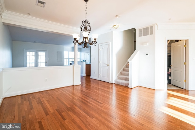 empty room with ornamental molding, light hardwood / wood-style flooring, and a notable chandelier