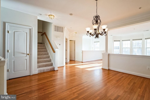 spare room featuring crown molding, light hardwood / wood-style floors, and an inviting chandelier