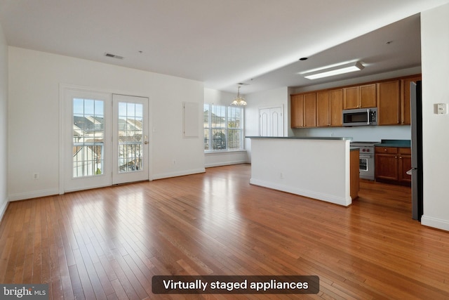 kitchen with hardwood / wood-style floors, a notable chandelier, and appliances with stainless steel finishes