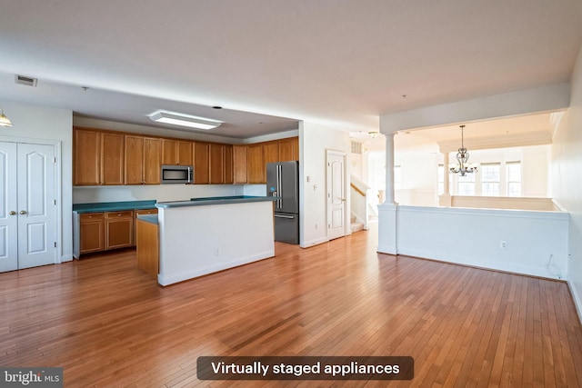 kitchen featuring an inviting chandelier, hardwood / wood-style flooring, decorative light fixtures, a kitchen island, and stainless steel appliances