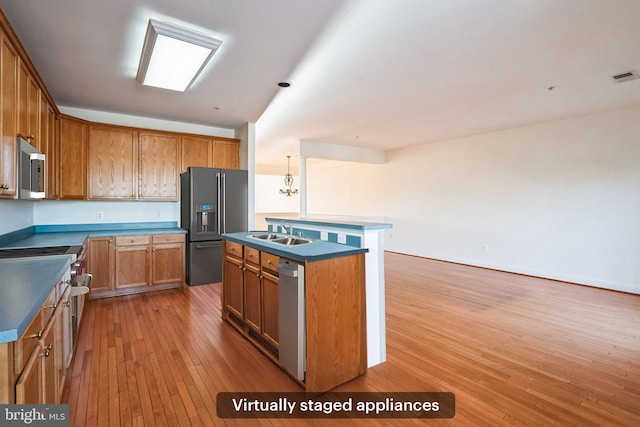 kitchen featuring a kitchen island with sink, sink, stainless steel appliances, and light wood-type flooring