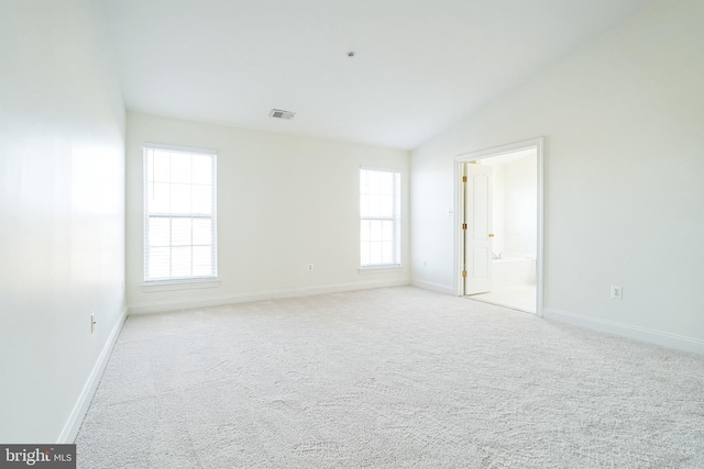 carpeted spare room featuring vaulted ceiling