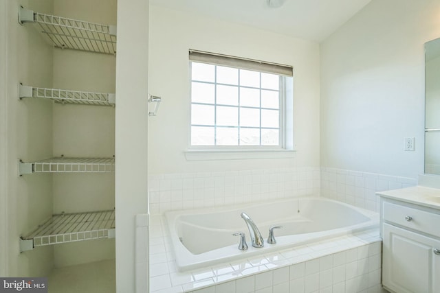 bathroom with tiled bath and vanity