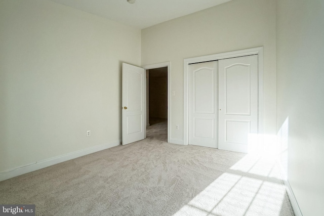 unfurnished bedroom featuring light carpet and a closet