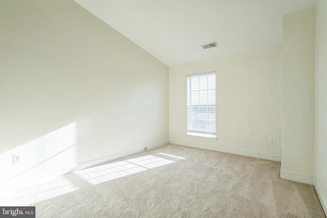 carpeted empty room featuring vaulted ceiling