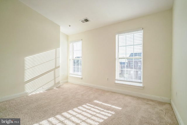 spare room featuring light colored carpet, a healthy amount of sunlight, and vaulted ceiling