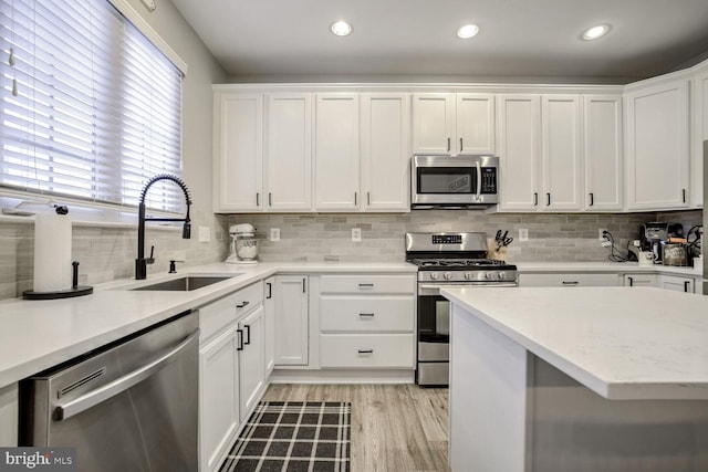 kitchen featuring white cabinets, decorative backsplash, sink, and stainless steel appliances