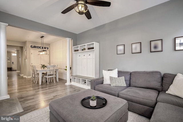 living room with ceiling fan with notable chandelier and hardwood / wood-style flooring