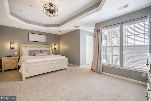 carpeted bedroom featuring a tray ceiling and a chandelier