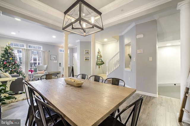 dining room with an inviting chandelier, decorative columns, light hardwood / wood-style flooring, and ornamental molding