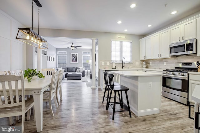 kitchen with a center island, hanging light fixtures, ceiling fan, appliances with stainless steel finishes, and light hardwood / wood-style floors