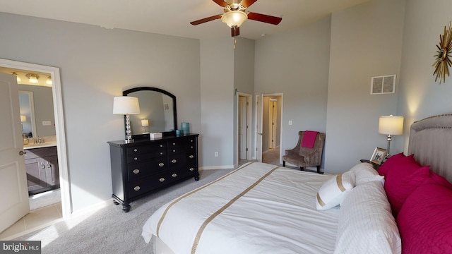 carpeted bedroom with ensuite bath, ceiling fan, and a high ceiling