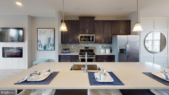 kitchen with a breakfast bar, stainless steel appliances, hanging light fixtures, and tasteful backsplash